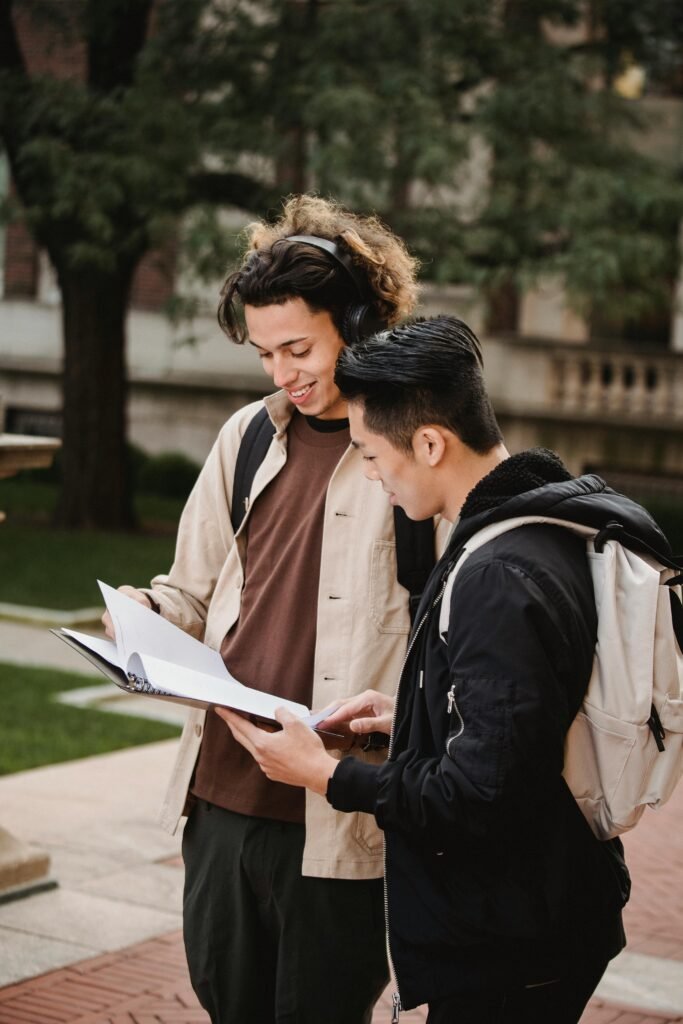 Two university students reviewing documents in a campus courtyard, engaging in academic discussion.